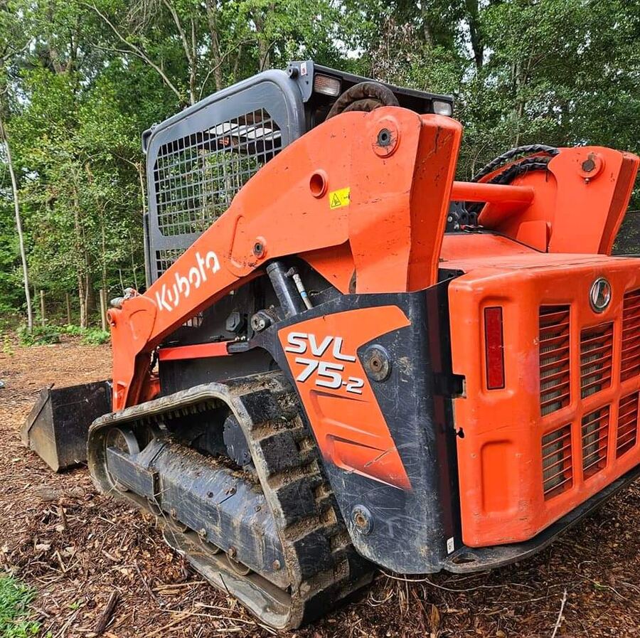 Compact track loader clearing a wooded lot for an outdoor space project